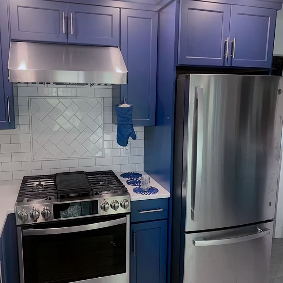 Blue kitchen with stainless steel appliances and white countertops.