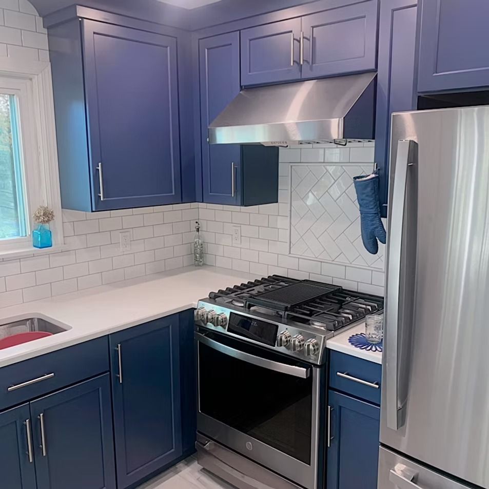 Blue kitchen with white countertops and subway tile backsplash; stainless steel appliances.