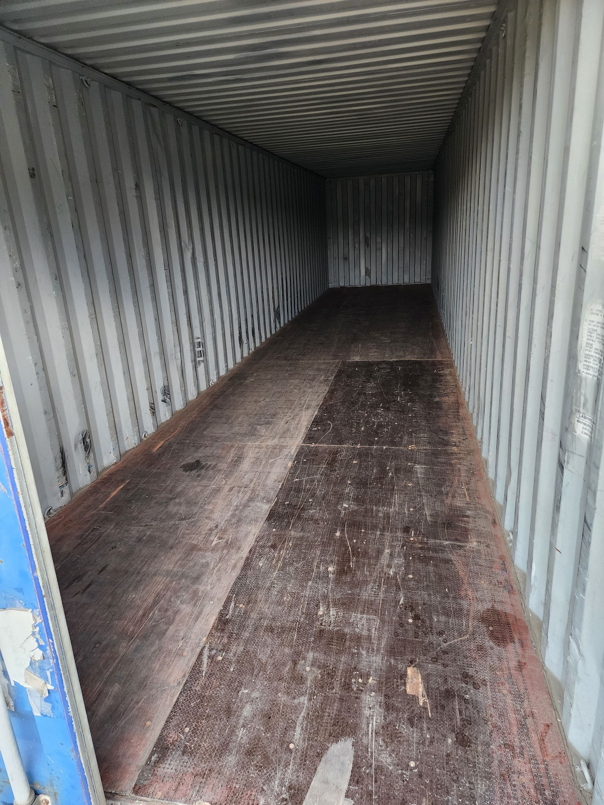 An empty shipping container with a lot of dirt on the floor.