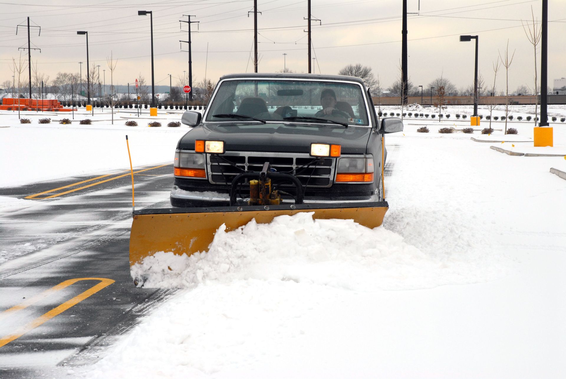 Truck plowing snow on a snowy road in a parking lot