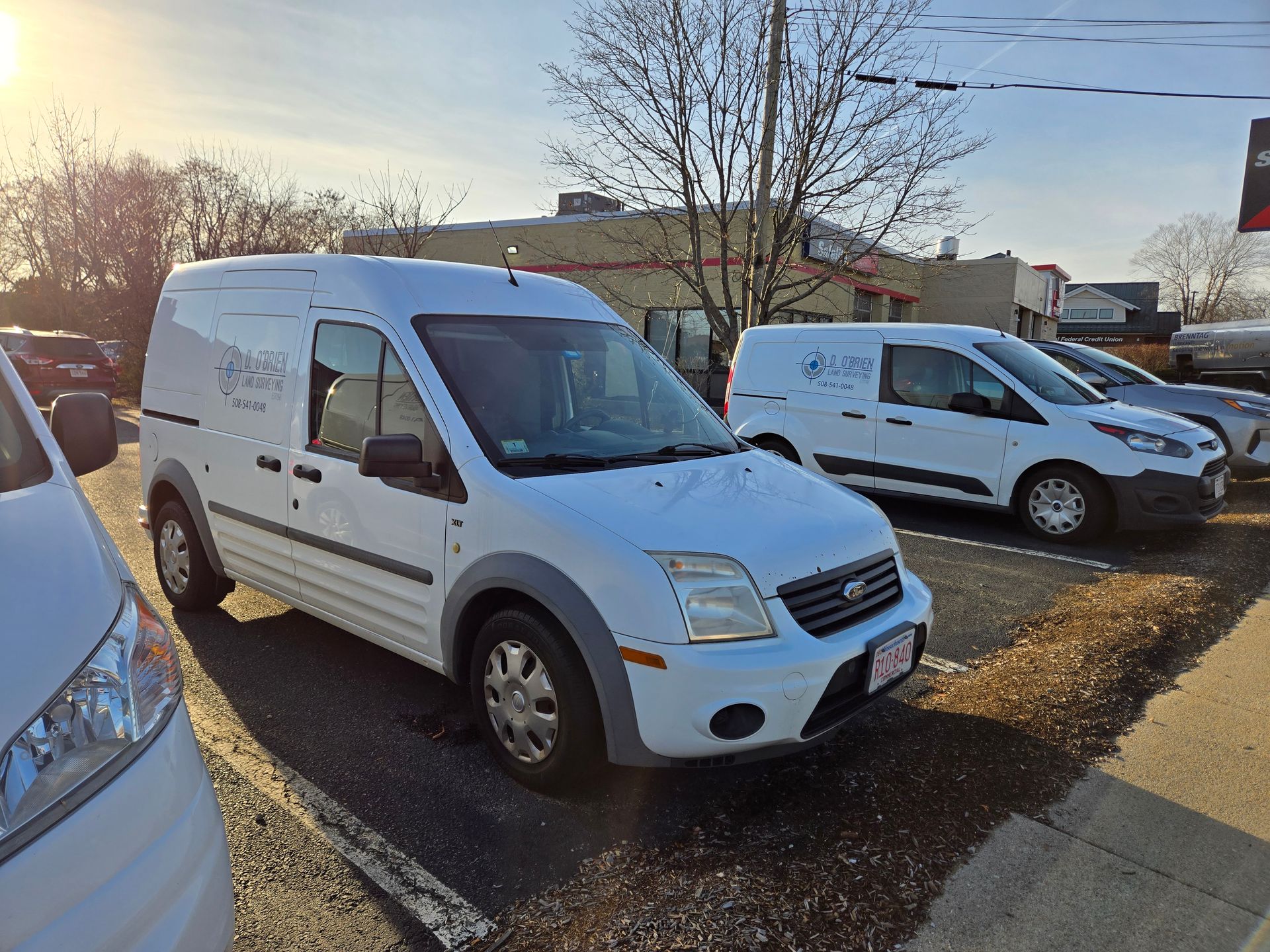 A row of white vans are parked in a parking lot.
