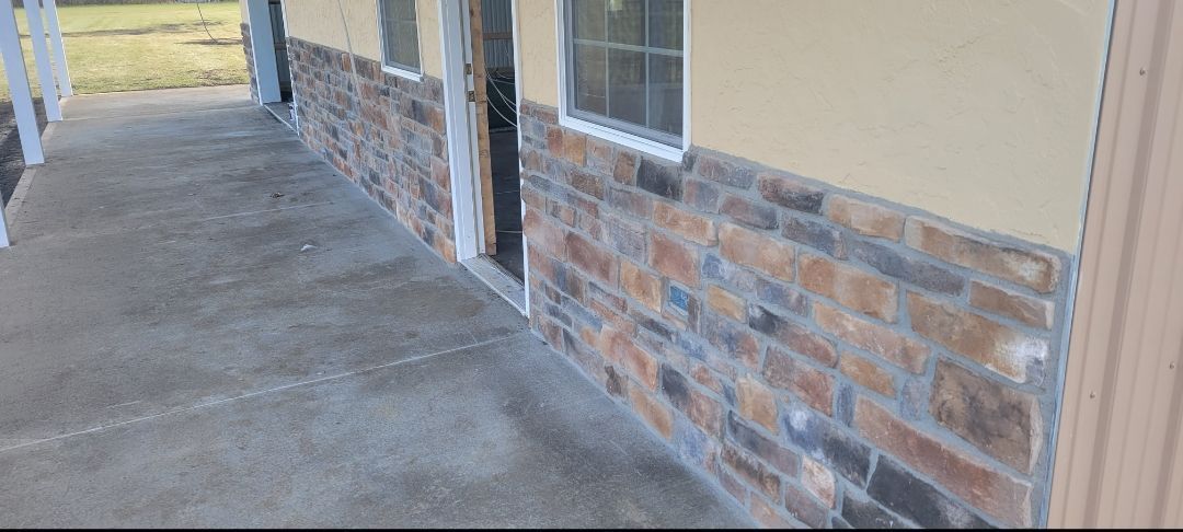 A concrete porch features an exterior wall finished with tan stucco on top and multi-colored stone veneer at the base.