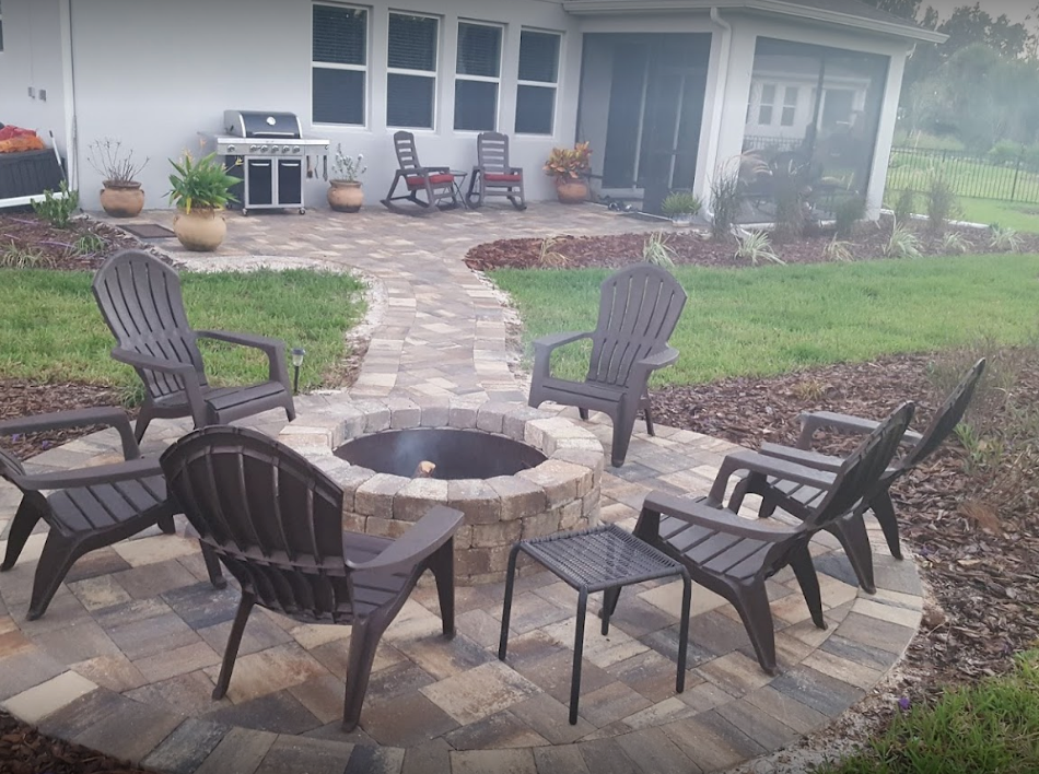 Patio with fire pit, seating, and walkway; home exterior in background.