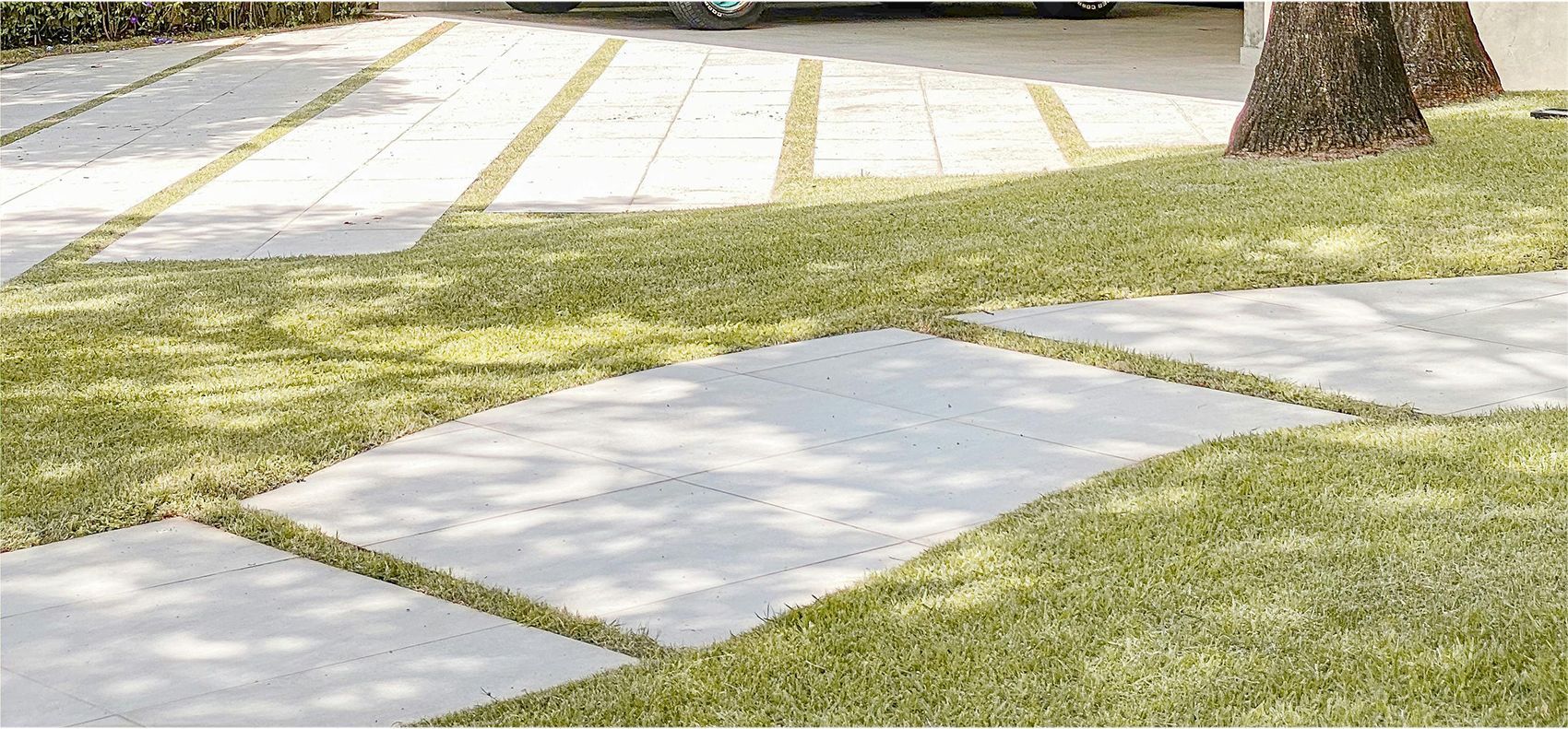Stone pavers with grass growing between them, in a yard.
