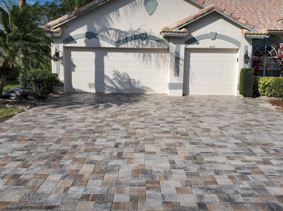 Paver driveway in front of a house with two garage doors.