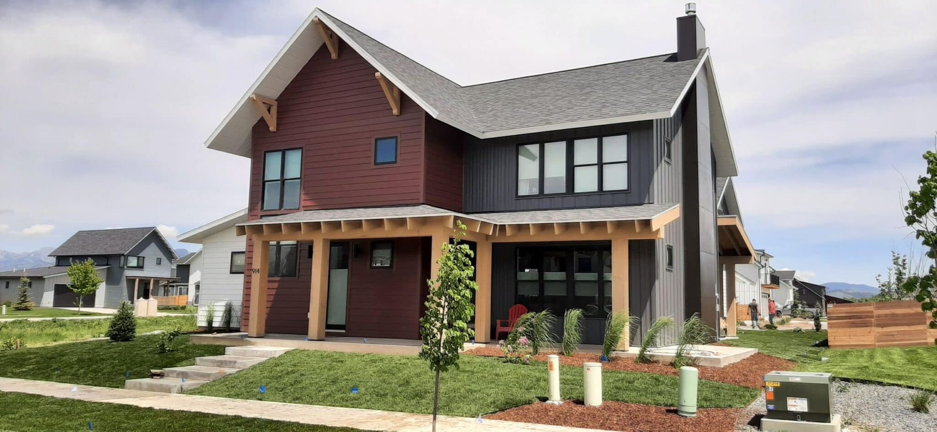 Modern two-story house with brick and gray siding, porch, and a landscaped yard.