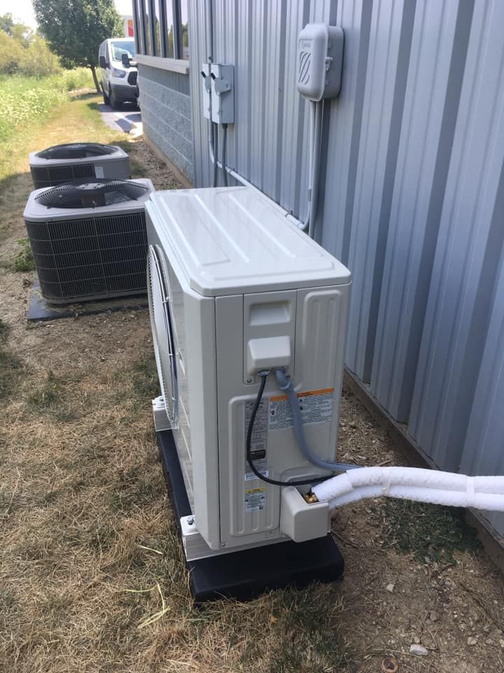 A white air conditioner is sitting on the side of a building.