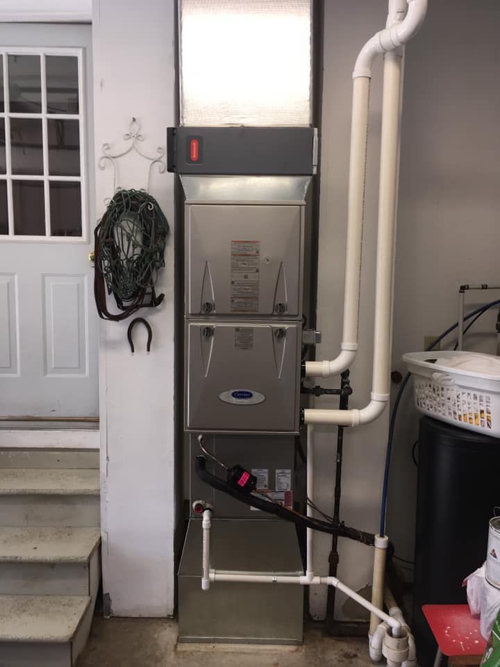 A stainless steel air conditioner is sitting in a basement next to a door.