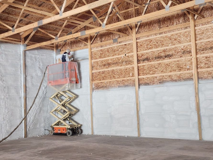 Person using a lift spraying insulation on a building's interior walls. 