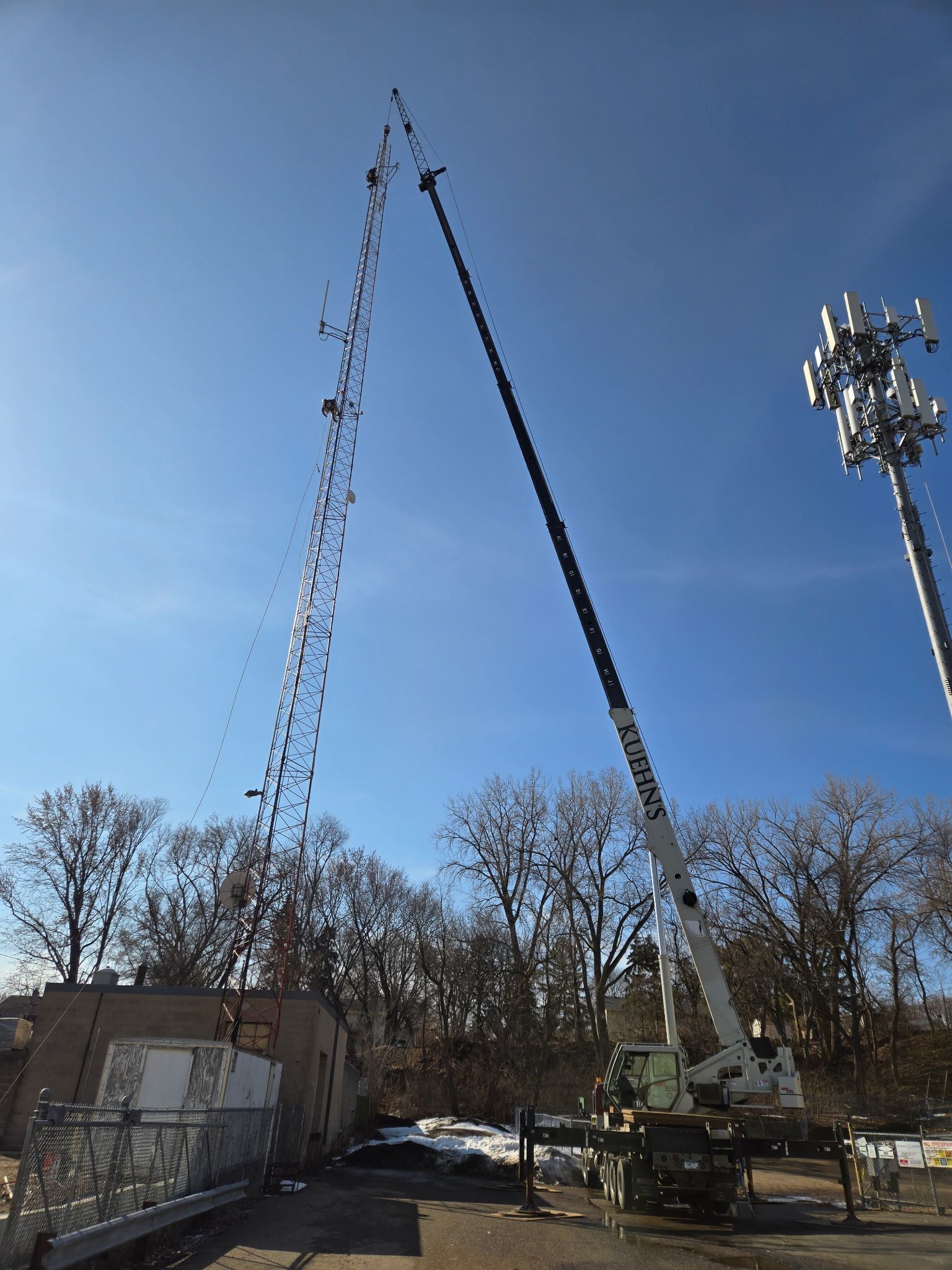 A large crane is working on a telephone pole