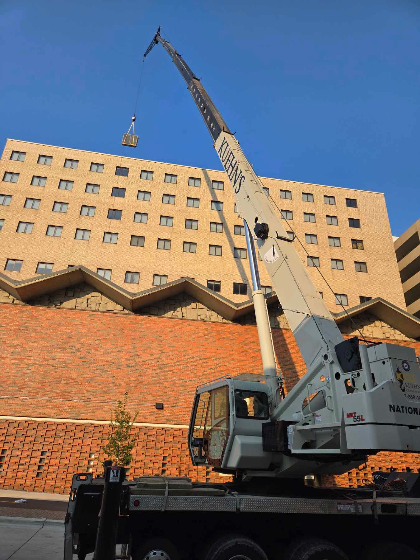 A large truck with a crane attached to it is parked in front of a large building