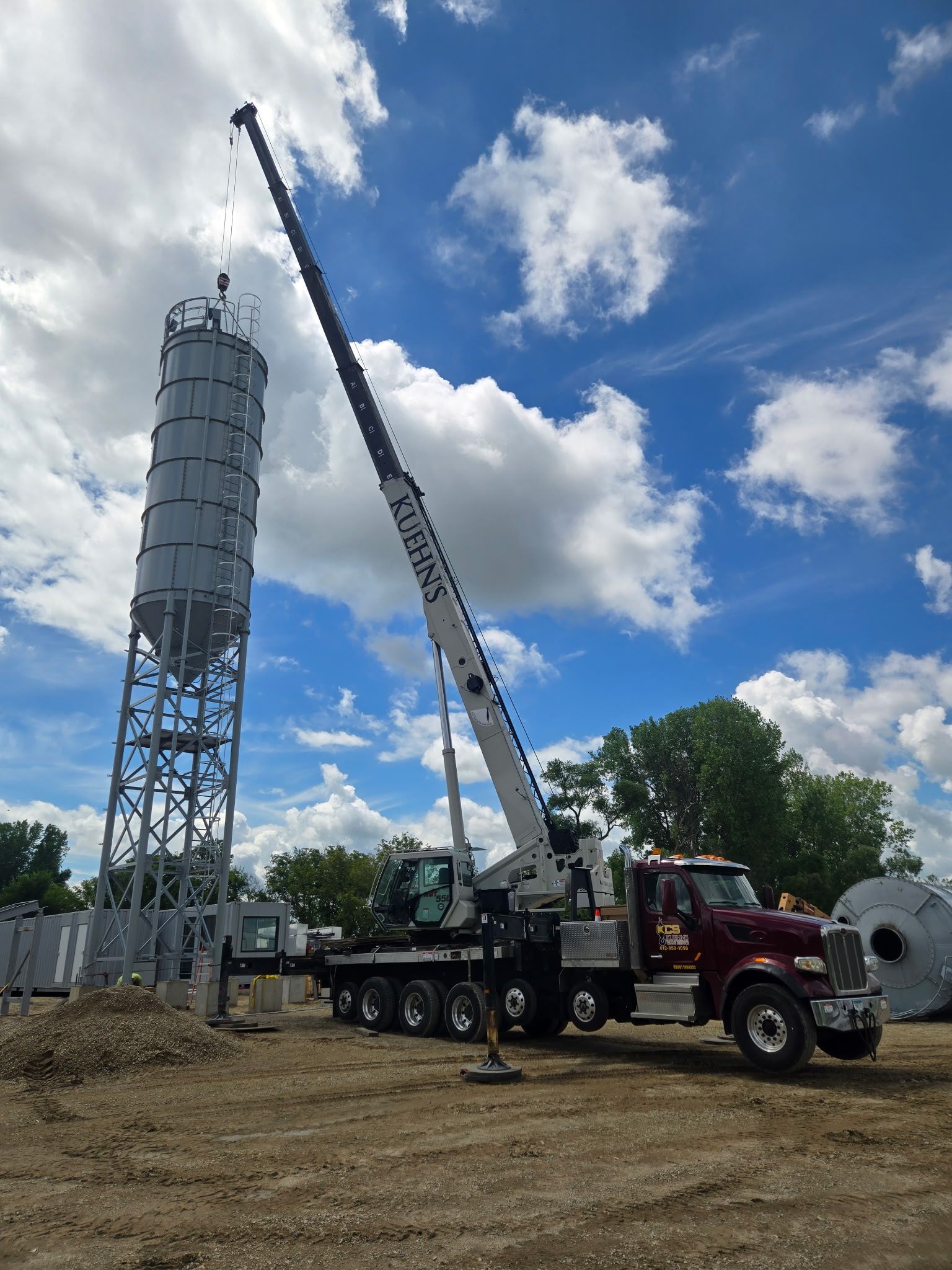 A truck with a crane attached to it is parked in a dirt field.