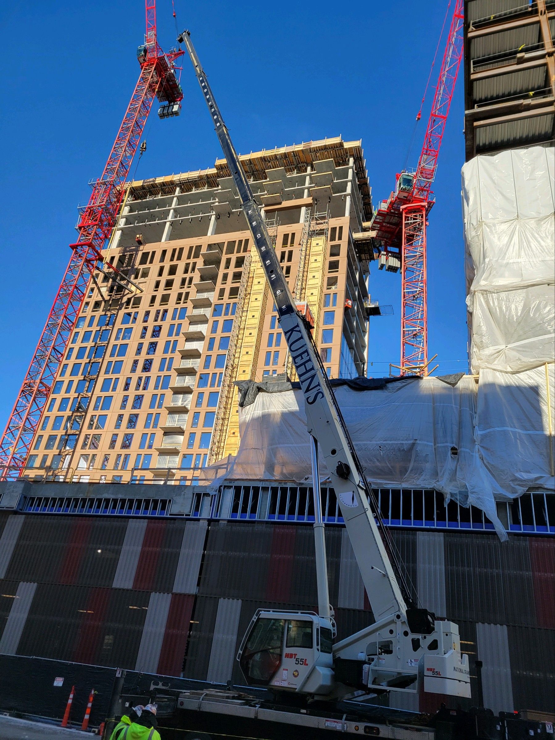 A large crane is sitting in front of a building under construction.