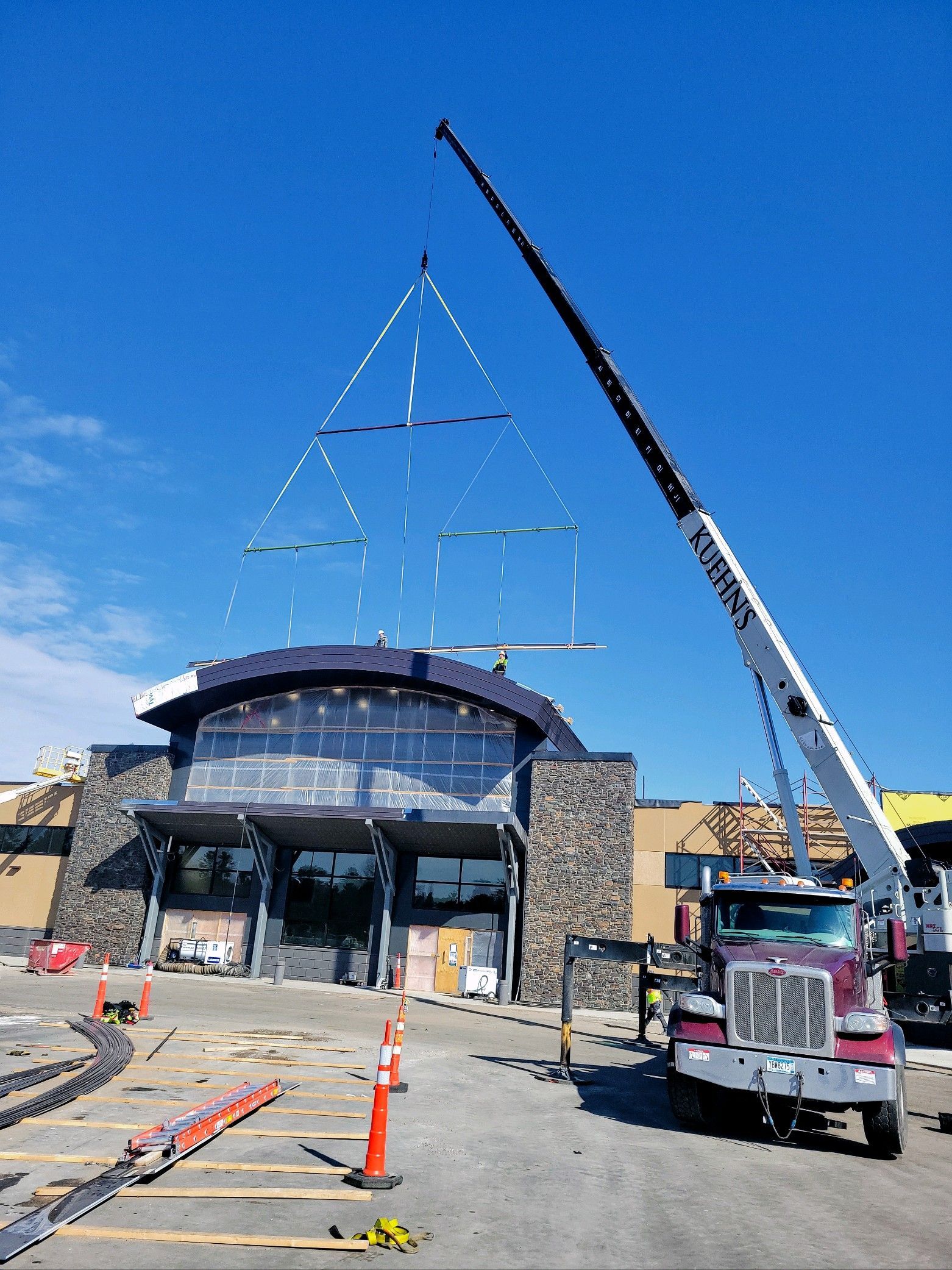A crane is lifting a triangle in front of a building under construction.