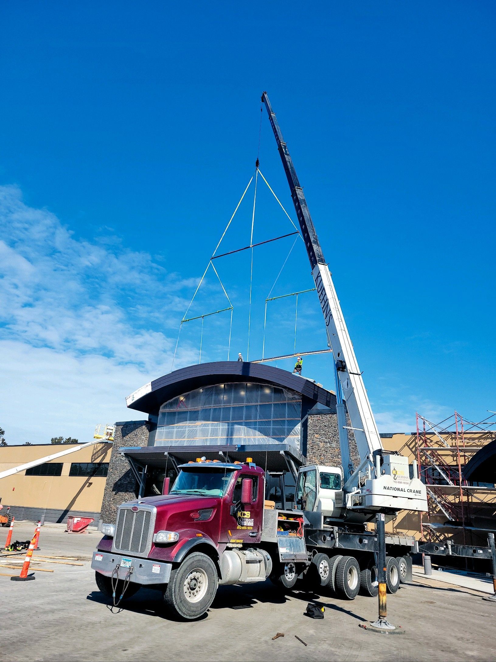 A truck with a crane attached to it is parked in front of a building under construction.