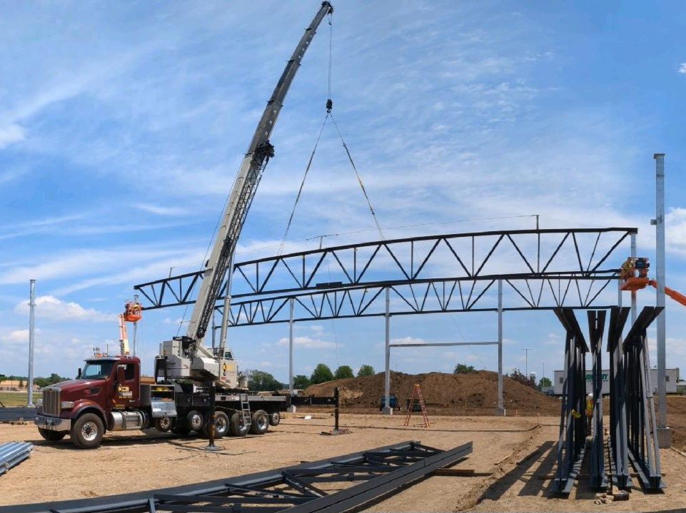 A truck is being lifted by a crane on a construction site.