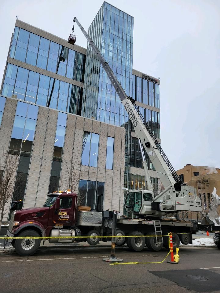 A truck with a crane on the back is parked in front of a tall building.