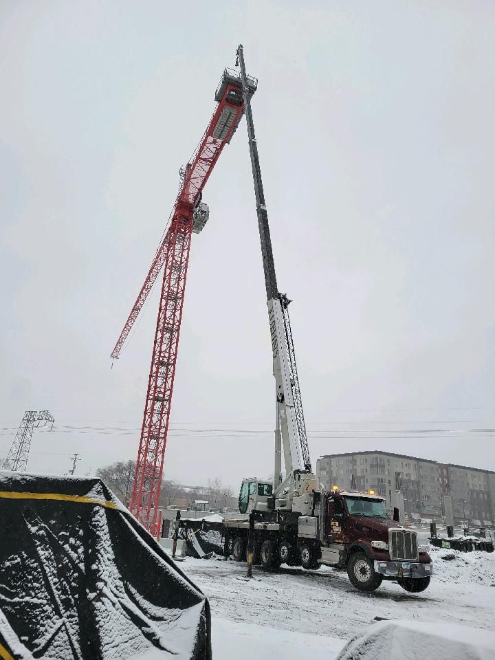 A crane is being lifted by a truck in the snow