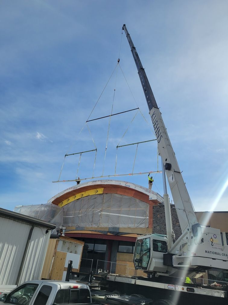 A large crane is lifting a roof of a building.
