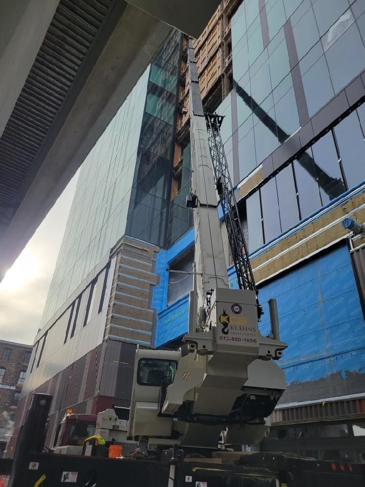 A large crane is sitting in front of a building under construction.