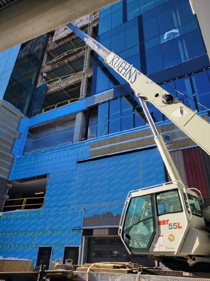 A large crane is sitting in front of a building under construction.