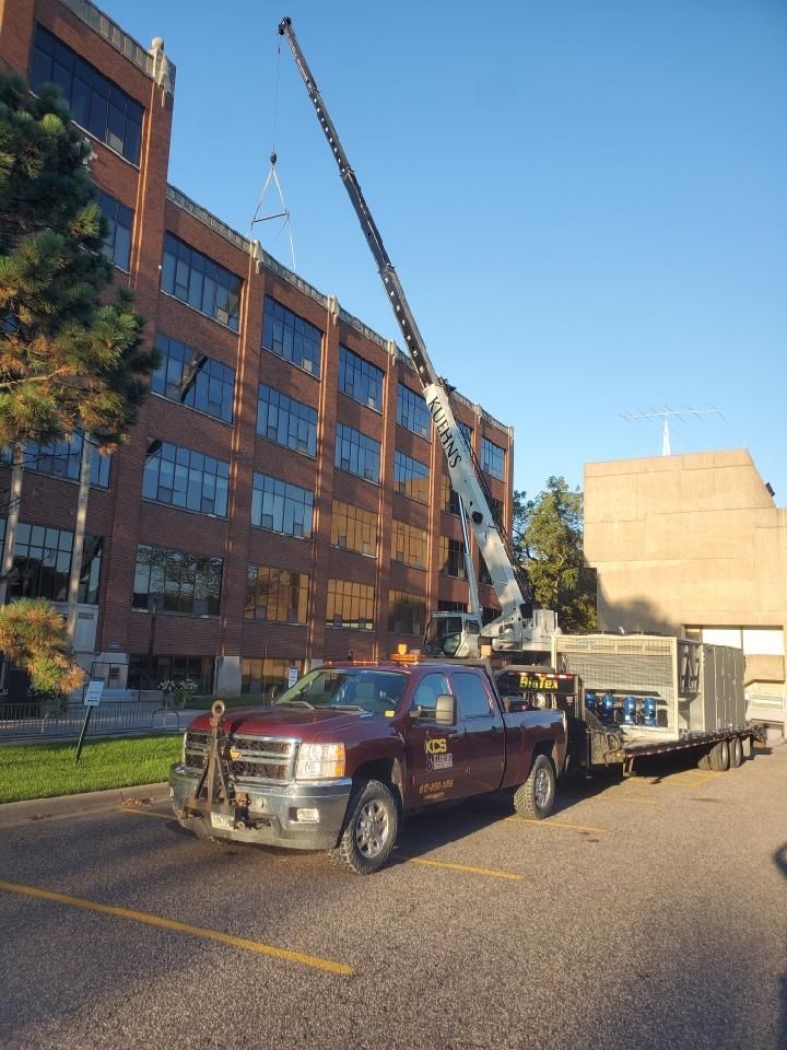 A red truck is parked in front of a large building