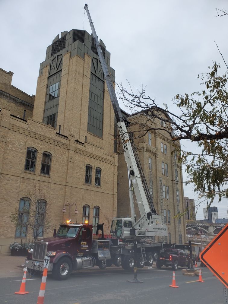 A truck with a crane attached to it is parked in front of a large building