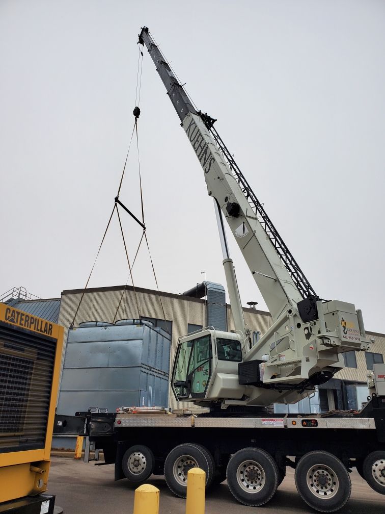 A large crane is lifting a large object in front of a building.