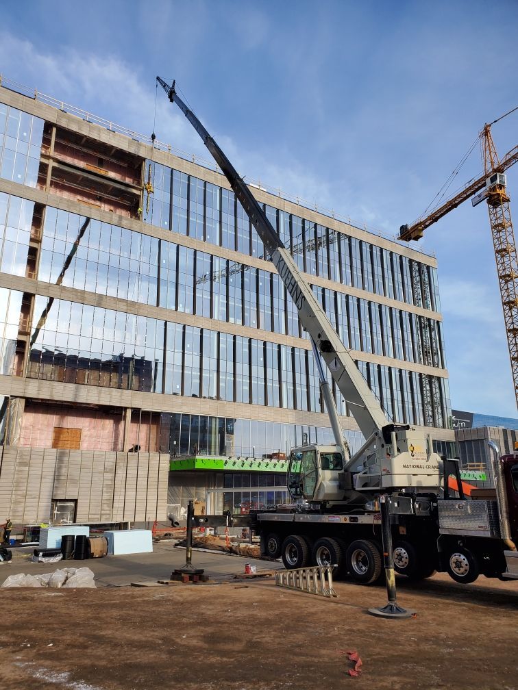 A large crane is sitting in front of a building under construction.