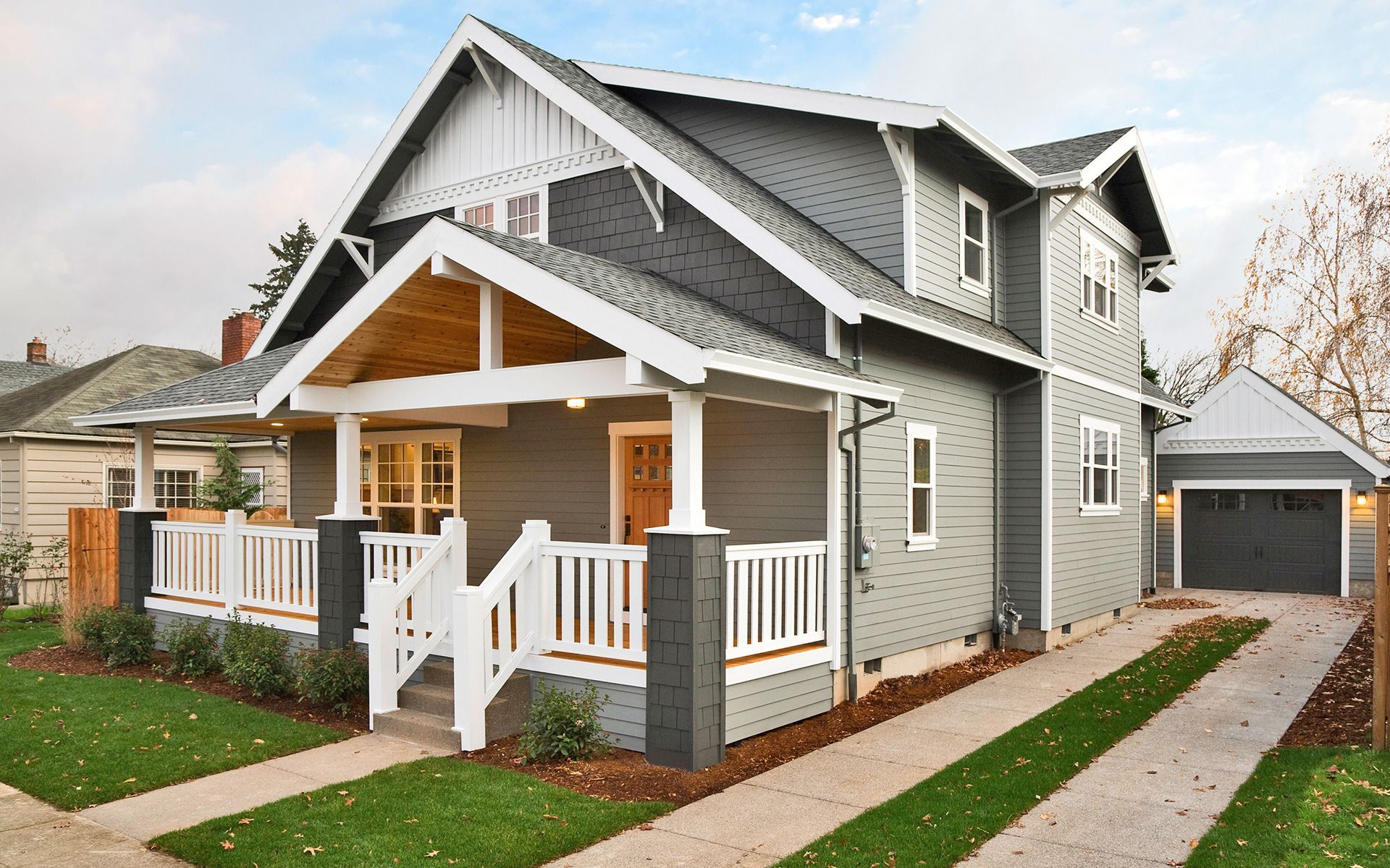 A large gray and white house with a porch and a garage.