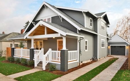 A large gray and white house with a porch and a garage.