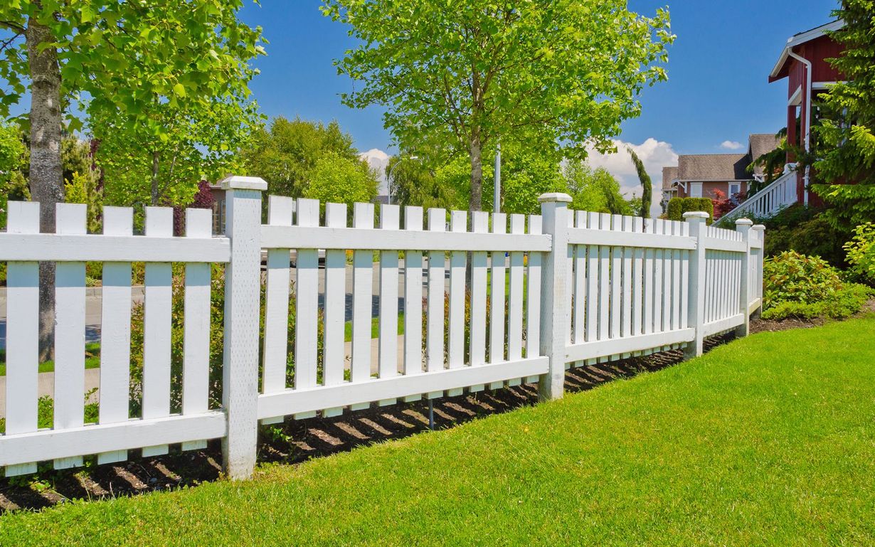 A white picket fence surrounds a lush green lawn.