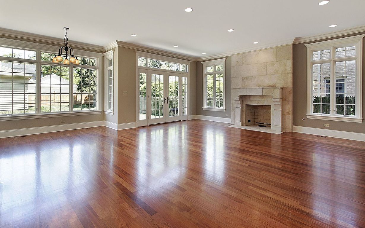 An empty living room with hardwood floors and a fireplace