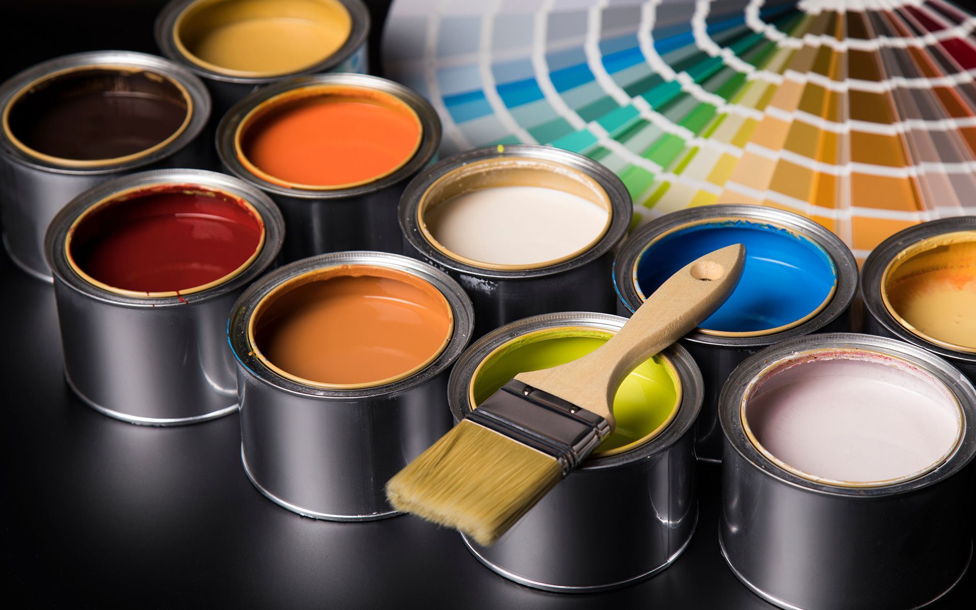 A bunch of cans of paint and a brush on a table