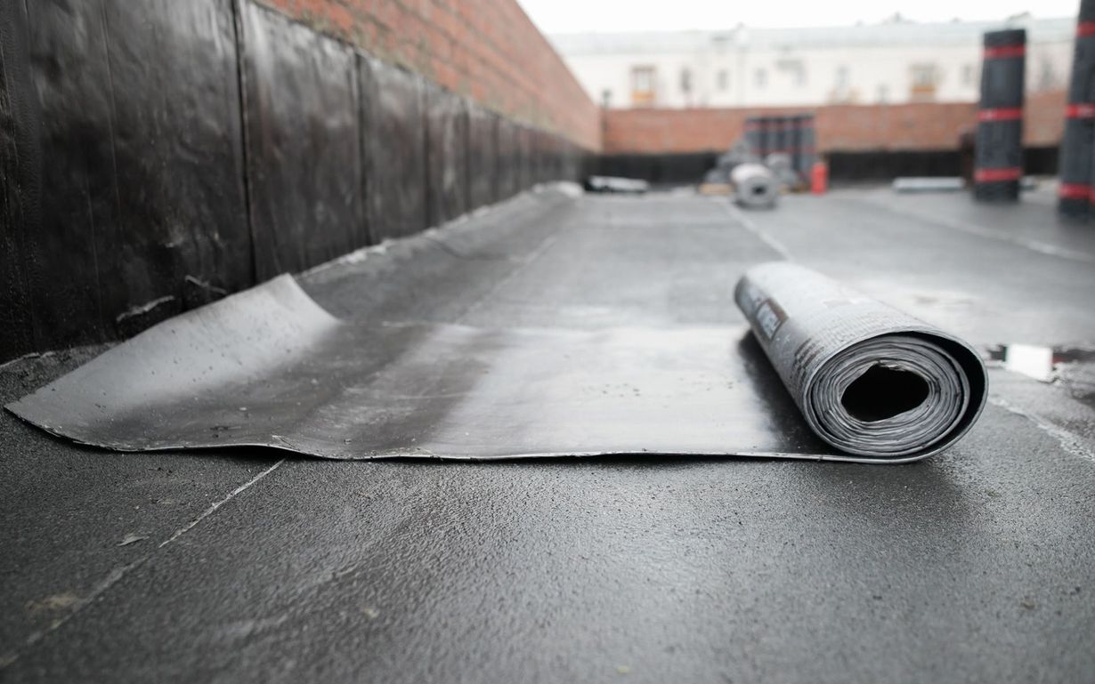 A roll of roofing material is laying on the ground.