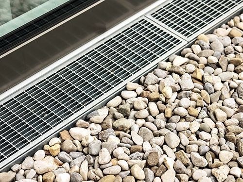 A metal grate is sitting on top of a pile of rocks.