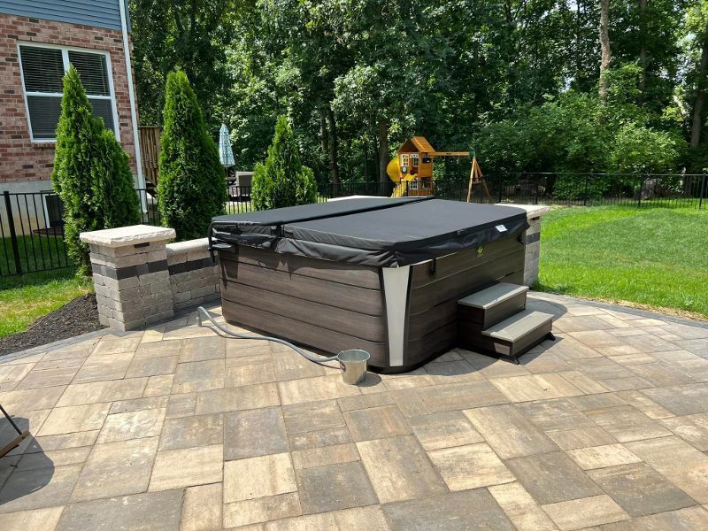 A hot tub is sitting on a patio next to a playground.