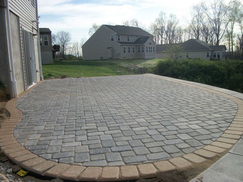 A brick patio is being built in front of a house.