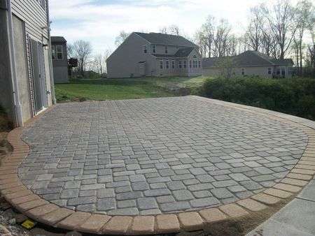 A brick patio is being built in front of a house.
