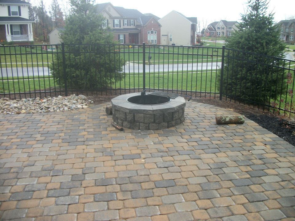 A brick patio with a fire pit in the middle