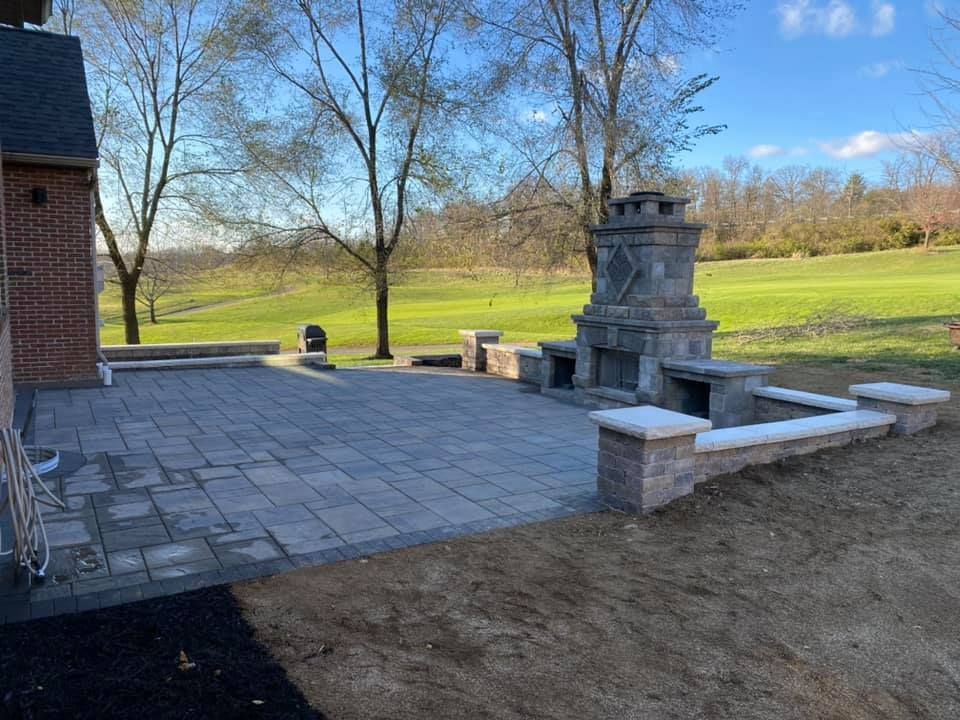 A patio with a fireplace and a fire pit in the backyard of a house.