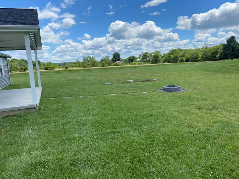 A large lush green field with a house in the background.