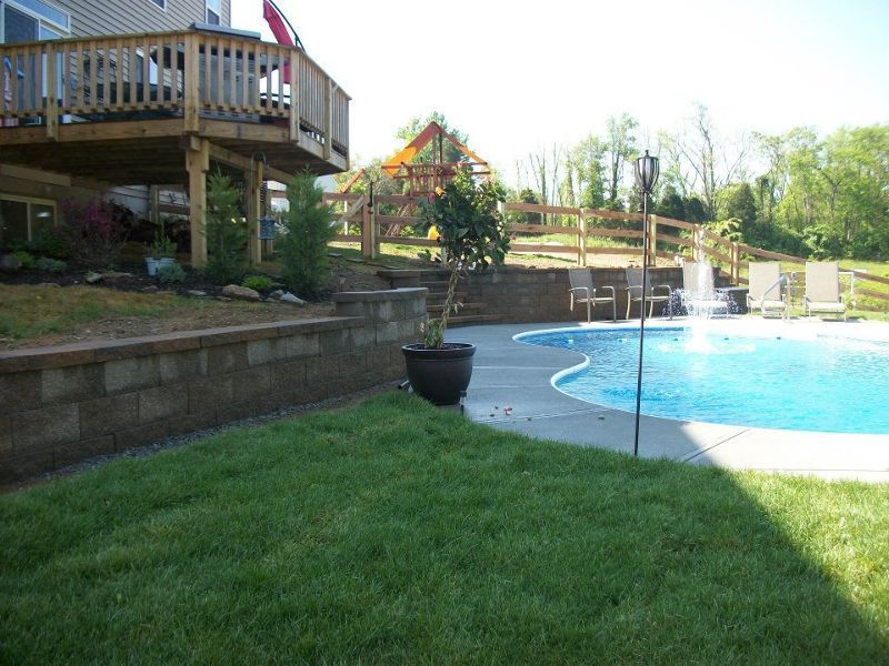 A large swimming pool in a backyard with a house in the background