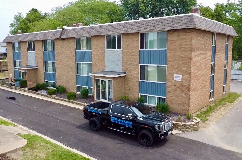Apartment building with blue panels, a black pickup truck parked in front.