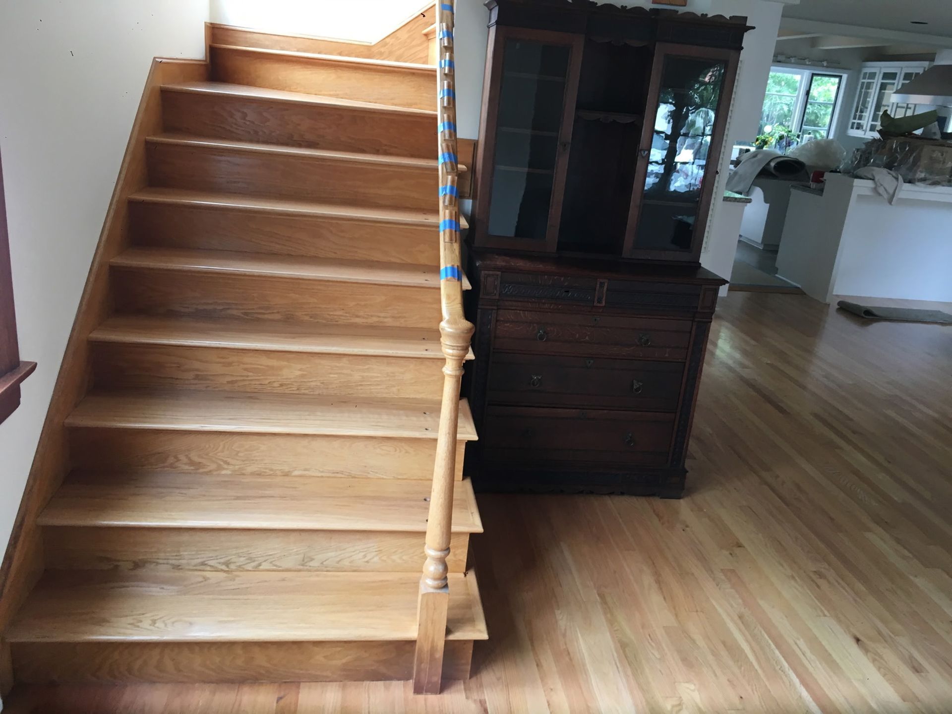 Wooden staircase next to a dark wood cabinet on a hardwood floor.