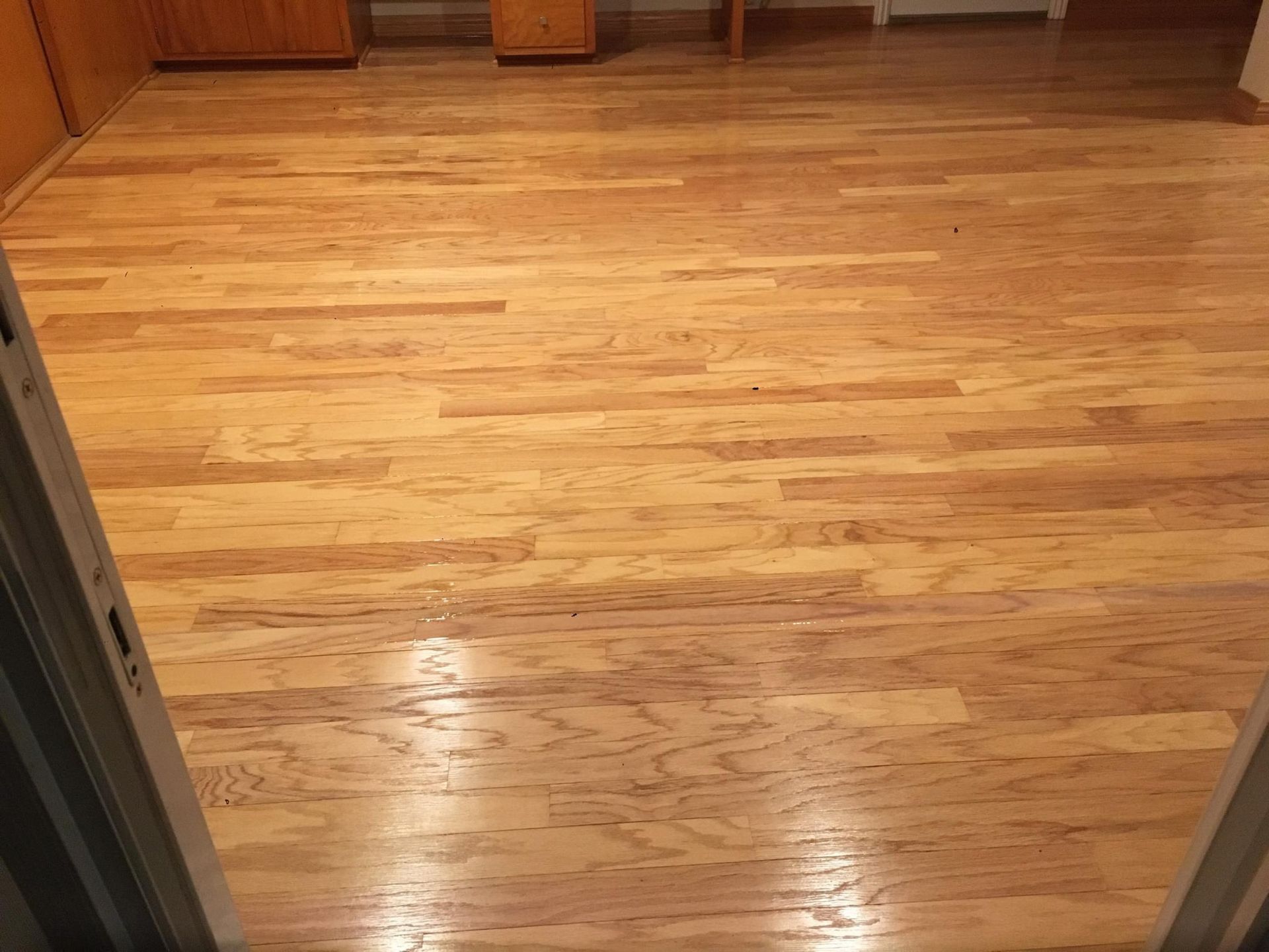 Hardwood flooring with light brown, natural wood grain patterns, viewed from a doorway.