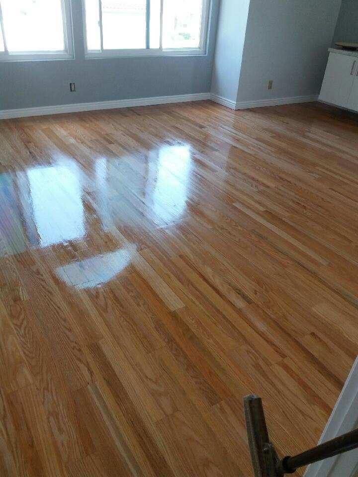 Refinished light-toned hardwood flooring in a bright, empty room with large windows.
