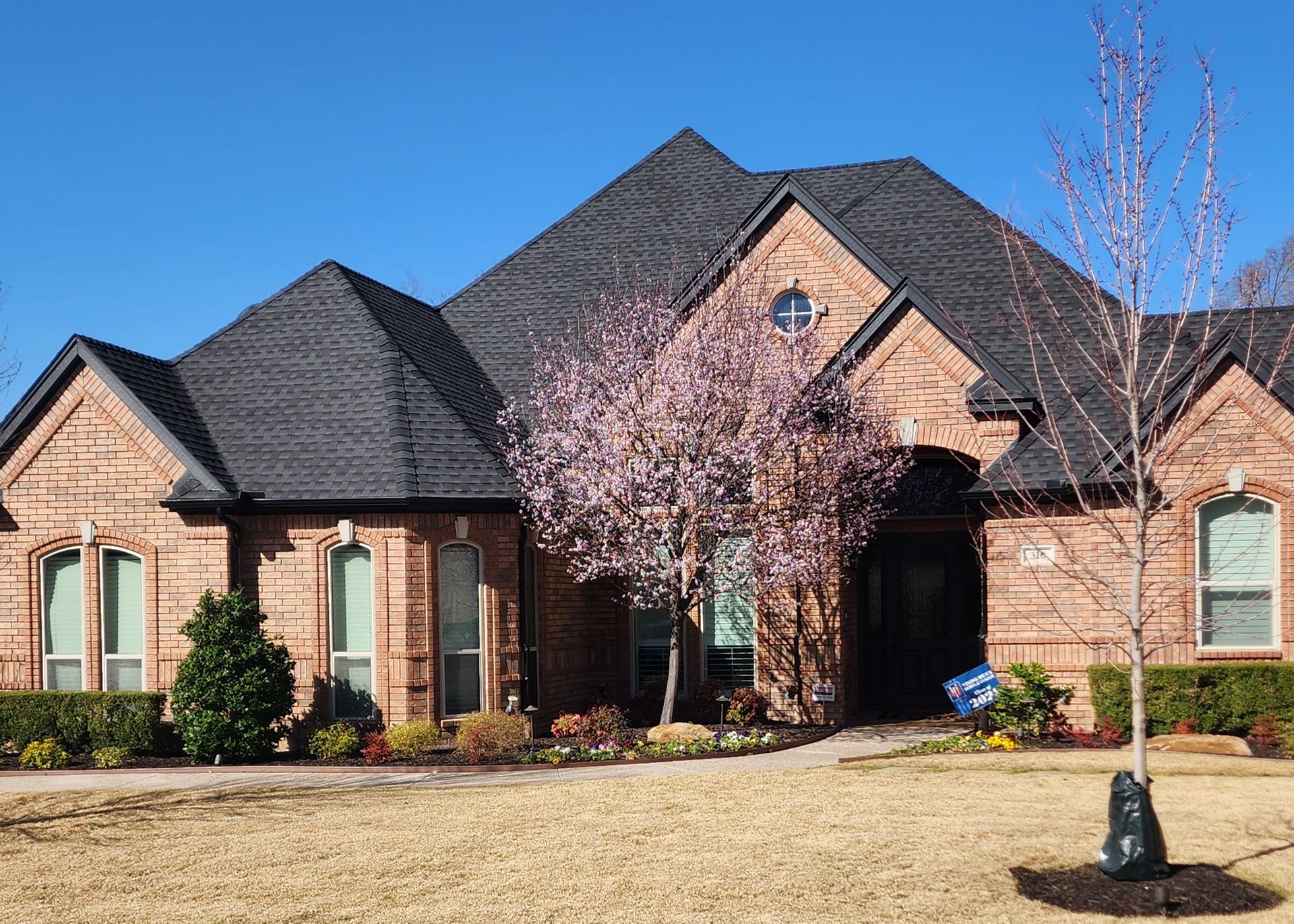 A large brick house with a for sale sign in front of it