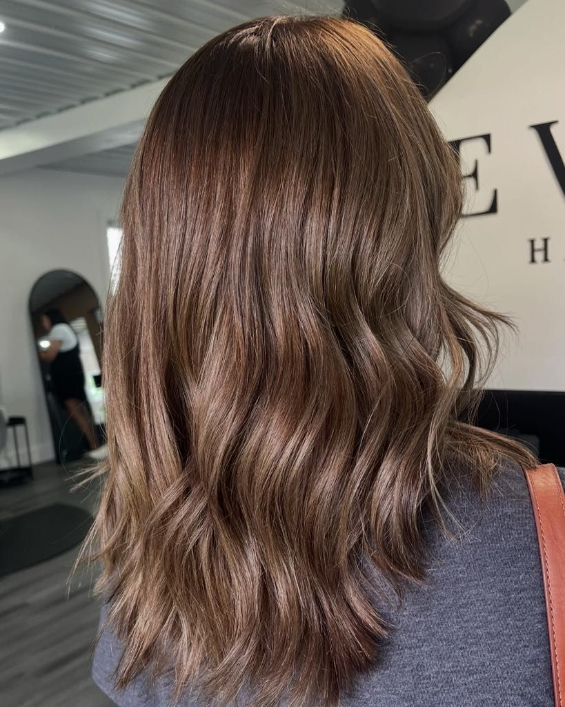 Woman with wavy, dark brown hair; indoors at a salon.