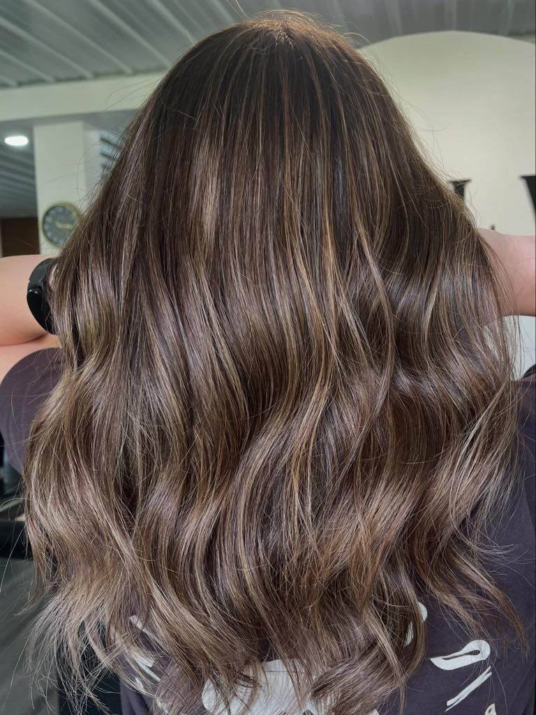 Woman's wavy brown hair with highlights. Salon setting.